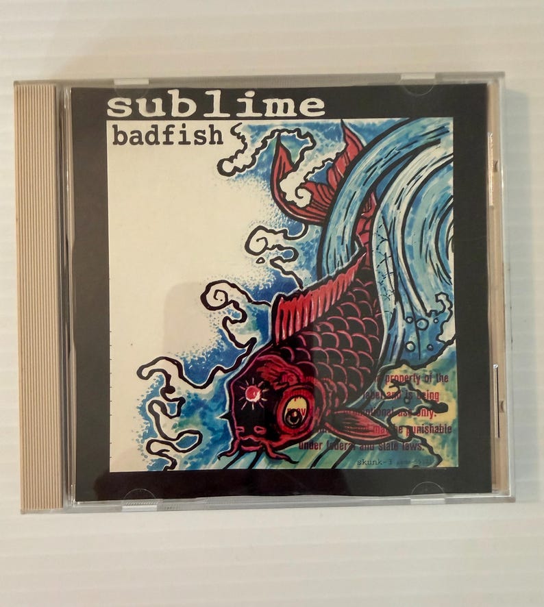 May include: CD case featuring the album "Badfish" by Sublime. The cover art displays a red and black koi fish with blue water elements. The band's name is in white text at the top.