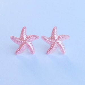 May include: A pair of pink starfish earrings. The starfish are made of a shiny, pearlescent material.