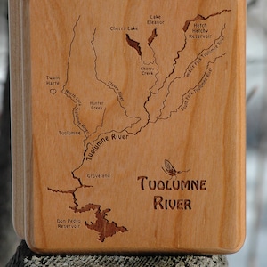 May include: A wooden box with a map of the Tuolumne River engraved on the lid. The map shows the river's course, including tributaries, lakes, and reservoirs. The text "Tuolumne River" is also engraved on the lid.