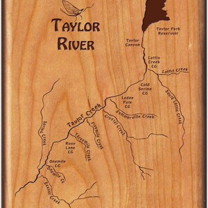 May include: Wooden plaque with a detailed map of the Taylor River, featuring tributaries and landmarks. The text "Taylor River" is prominently displayed, along with the names of creeks and campgrounds. A decorative insect is above the river name.