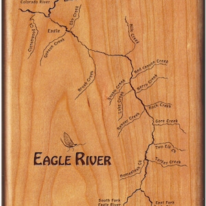 May include: A wooden map of the Eagle River in Colorado, with the names of various creeks and rivers engraved on the surface. The map features a stylized image of a fly fisherman's fly.