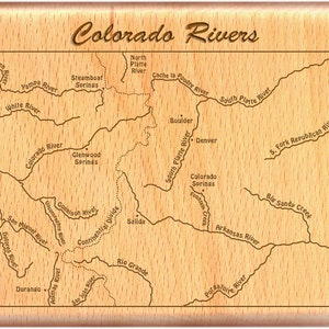 May include: A wood-grain map of Colorado rivers, with the names of the rivers and towns labeled in brown text. The map is surrounded by a brown frame.