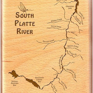 May include: A wooden map of the South Platte River in Colorado, with the names of various creeks and reservoirs labeled. The map is carved into the wood and has a light brown color.
