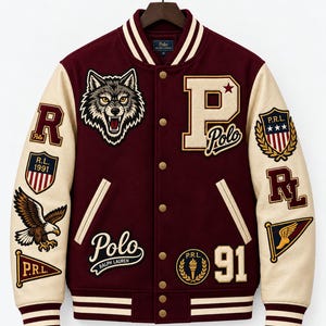Pode incluir: Uma jaqueta varsity bordô com mangas na cor creme, apresentando vários emblemas bordados, incluindo uma cabeça de lobo, uma letra P grande, uma águia e o texto Polo Ralph Lauren, P.R.L. 1991 e 91, com gola e punhos canelados listrados.