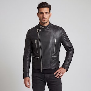 May include: A black leather motorcycle jacket featuring an asymmetrical silver-tone zipper closure, a snap-button collar, quilted shoulder detailing, and multiple zippered pockets on the front. The jacket includes adjustable side buckles at the waist.