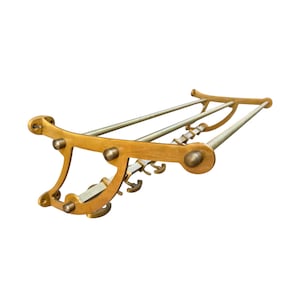 May include: A wall-mounted coat rack constructed from polished brass, featuring two horizontal bars for hanging items and a series of small, curved hooks attached to the lower frame. The structure includes decorative side brackets with rounded ends.