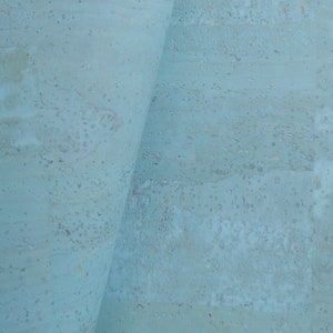May include: A close-up of a light blue cork board with a tan piece of cork folded over the top edge.