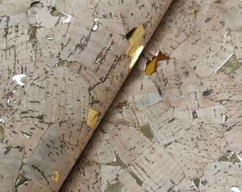 May include: Close-up of a sheet of cork material with a natural, light brown color. The cork has a mosaic-like pattern with irregular shapes and gold metallic accents. The material is folded over, revealing the underside.