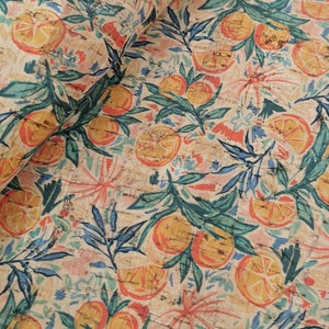 May include: A beige fabric with a repeating pattern of orange slices, green leaves, and blue floral designs. The fabric has a cork-like texture.