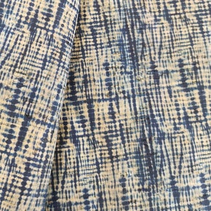 May include: Close-up of a fabric with a blue and white geometric pattern. The fabric has a textured surface and a subtle sheen.