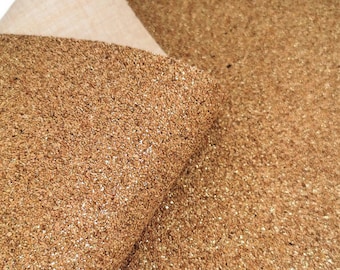 May include: A close-up of a sheet of gold glitter fabric. The fabric has a textured, cork-like appearance.
