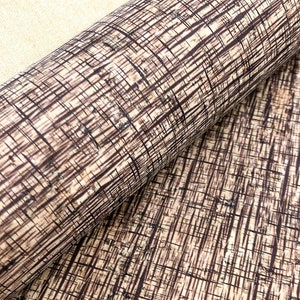 May include: A close-up of a brown and beige cork fabric with a woven pattern. The fabric has a natural, rustic look.