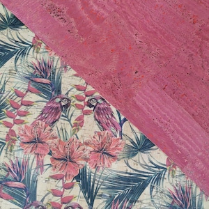 Könnte beinhalten: Nahaufnahme eines rosafarbenen Korkbretts mit einem tropischen bedruckten Stoff darunter. Der Stoff zeigt rosa Hibiskusblüten, grüne Palmblätter und rosa Papageien.