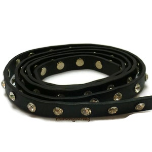 May include: Black leather trim with silver studs and clear rhinestones. The trim is rolled up and ready to be used for a craft project.