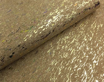May include: A close-up of a sheet of cork fabric with a gold metallic finish. The cork has a natural brown color with flecks of yellow, green, and purple. The fabric has a textured surface.