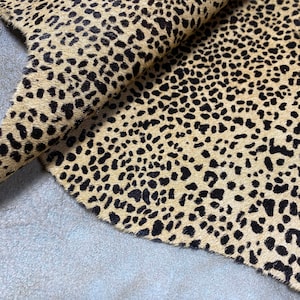 Può includere: Primo piano di un tessuto con stampa animalier marrone e nero con un motivo a stampa leopardata.