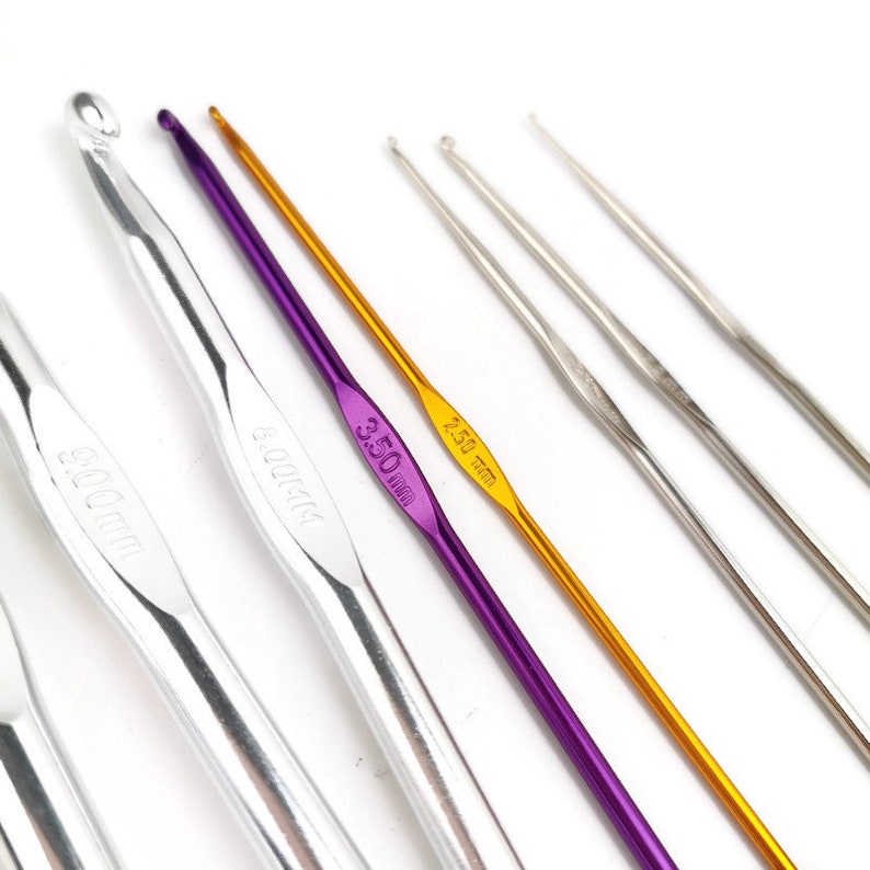 May include: A set of six crochet hooks in various sizes, including 3.50 mm, 4.00 mm, and 5.00 mm. The hooks are made of aluminum and have a silver, purple, and gold finish.