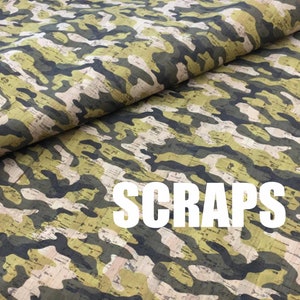 Puede incluir: Primer plano de una tela con un patrón de camuflaje en tonos de verde, marrón y beige. La tela tiene una textura de corcho. La palabra "SCRAPS" está impresa en letras blancas sobre la tela.