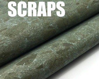 May include: Close-up of a textured, green and brown cork fabric with the word "SCRAPS" printed in white.