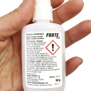 May include: A white bottle of Forte Plus instant adhesive, labelled for use on footwear and leather. The bottle contains 50 grams of adhesive and has a warning label with an exclamation point.