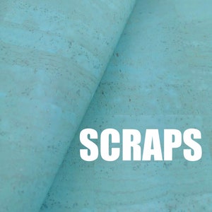 Puede incluir: Una hoja de tela de corcho azul claro con una textura natural moteada, doblada para mostrar la flexibilidad del material. La palabra SCRAPS está impresa en letras mayúsculas blancas, grandes y en negrita en la parte inferior de la imagen.