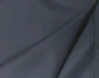 Pode incluir: Um close-up de um tecido cinza escuro com uma textura lisa. O tecido está dobrado ao meio, mostrando o interior da dobra.