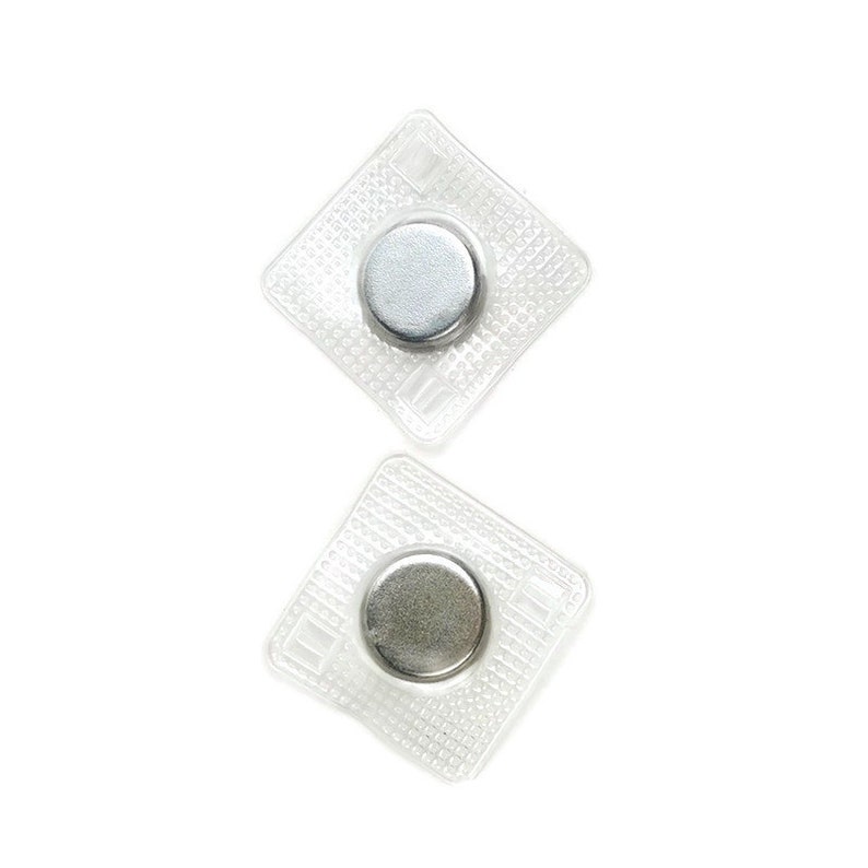 May include: Two clear plastic squares with a silver magnetic button in the center of each. The squares have a textured pattern.