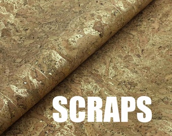 May include: A close-up of a sheet of cork fabric with a gold flecked pattern. The fabric is folded in half and the word "SCRAPS" is printed in white letters on the fabric.