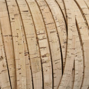 Puede incluir: Primer plano de un rollo de tiras de corcho natural. El corcho tiene un color marrón claro con marcas marrones más oscuras y una superficie texturizada. Las tiras están enrolladas, mostrando la flexibilidad y el grano natural.