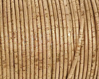 Può includere: Primo piano di un rotolo di cordoncino di sughero dorato. Il cordoncino è fatto di sughero naturale e ha un leggero luccichio.
