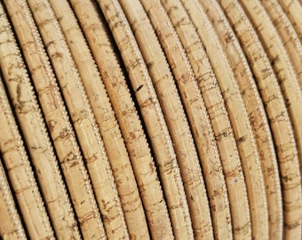 Può includere: Primo piano di un rotolo di cordoncino in sughero naturale, un materiale testurizzato di colore marrone chiaro. Il cordoncino è avvolto stretto, mostrando i dettagli della venatura naturale del sughero.