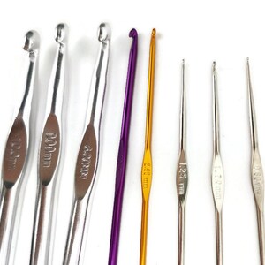 May include: Set of eight crochet hooks in various sizes, including 4.00 mm, 5.00 mm, 6.00 mm, 12.5 mm, 1.75 mm, 2.50 mm, and 3.50 mm. The hooks are made of metal and have a silver or gold finish.