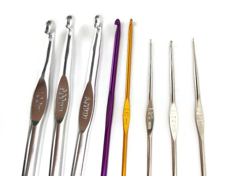 May include: Set of eight crochet hooks in various sizes, including 4.00 mm, 5.00 mm, 6.00 mm, 12.5 mm, 1.75 mm, 2.50 mm, and 3.50 mm. The hooks are made of metal and have a silver or gold finish.