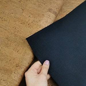 May include: A piece of cork fabric in a light brown colour with a dark brown piece of fabric on top of it.