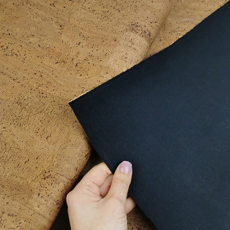 May include: A piece of cork fabric in a light brown colour with a dark brown piece of fabric on top of it.