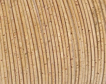 Può includere: Primo piano di un rotolo di cordoncino in sughero naturale. Il cordoncino è di colore beige chiaro e ha una superficie leggermente ruvida.