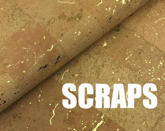 May include: A close-up of a sheet of cork with gold flecks. The cork is folded over, and the word "SCRAPS" is printed in white letters on the sheet.