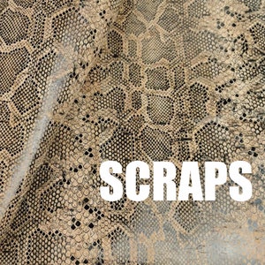 Könnte beinhalten: Nahaufnahme eines beige-schwarzen Schlangenlederstoffs mit dem in weißen Buchstaben gedruckten Wort "SCRAPS".