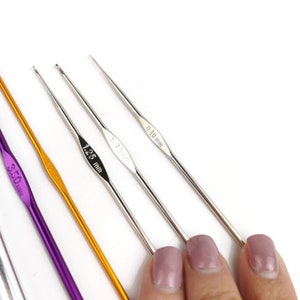 May include: Four crochet hooks of different sizes and colors. The hooks are labeled with their sizes in millimeters: 3.50 mm, 2.50 mm, 1.75 mm, and 0.30 mm.
