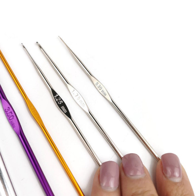 May include: Four crochet hooks of different sizes and colors. The hooks are labeled with their sizes in millimeters: 3.50 mm, 2.50 mm, 1.75 mm, and 0.30 mm.
