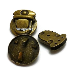 May include: Three antique gold-toned metal clasps for bags or purses. The clasps have a decorative design and are made of a durable metal.