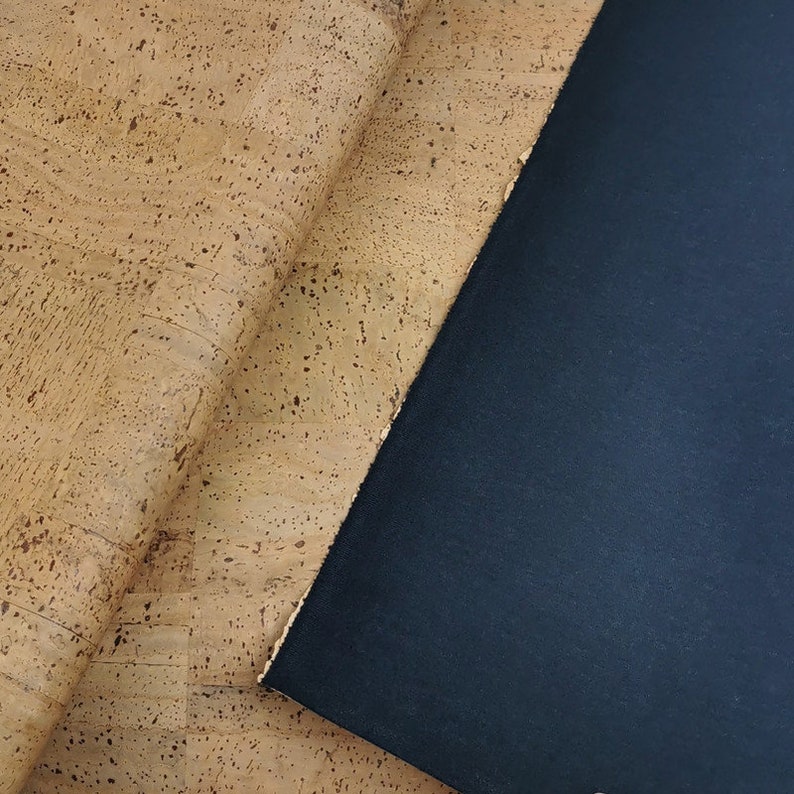 May include: A close-up of a piece of cork fabric with a dark blue fabric underneath.
