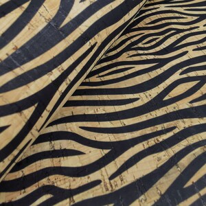 May include: Close-up of a cork fabric with a black and tan zebra print pattern.
