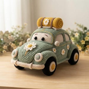 May include: A sage green crocheted toy car featuring a cream-colored roof, black wheels with yellow centers, and white daisy appliques on the hood and sides. A mustard yellow crocheted sleeping bag is secured to the roof with a white daisy accent.