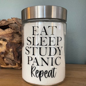 May include: A clear glass jar with a silver lid and a white label that reads "Eat Sleep Study Panic Repeat".