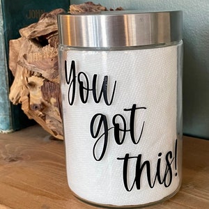 May include: A clear glass jar with a silver lid, filled with white paper towels. The jar has a black vinyl decal that reads "You got this!"