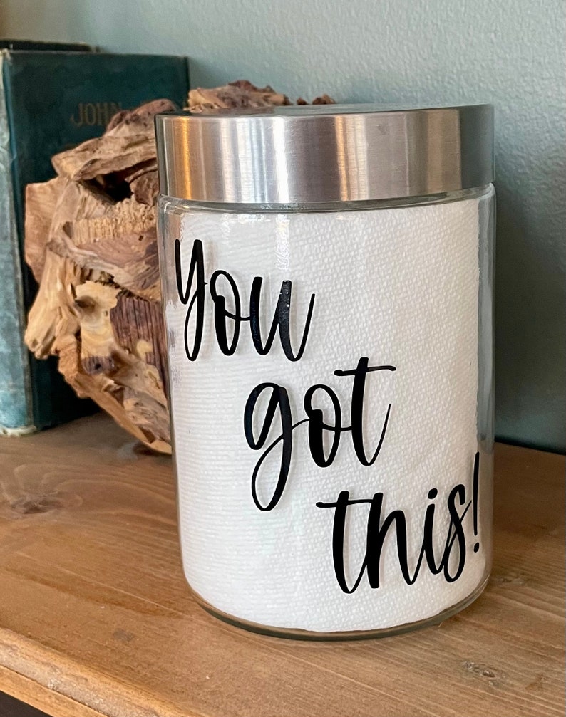 May include: A clear glass jar with a silver lid, filled with white paper towels. The jar has a black vinyl decal that reads "You got this!"