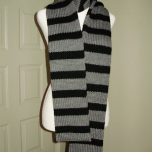 May include: A gray and black striped knit scarf. The scarf is folded in half and draped over a mannequin.