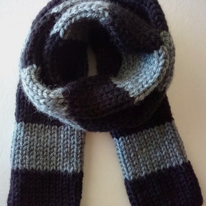 May include: A black and gray striped knitted scarf. The scarf is folded in half and the ends are hanging down.