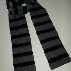 May include: A gray and black striped knitted scarf. The scarf is folded in half and the ends are hanging down.